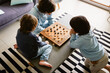 © Anna - Brothers playing the checkers at home, siblings playing the board strategy game, spending time together.