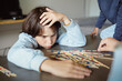 © Anna - Young teenager boy is concentrated while playing Mikado board game at home with his siblings. Family time together.