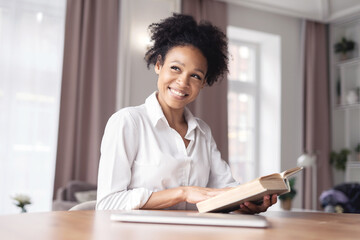 Wall Mural - A woman online learning at home reading a book doing a task