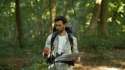 active man tourist got lost during hiking trip in woodland, looking for right way with compass and p