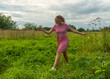 © Dmitry - a girl in a red dress runs through a meadow with green grass