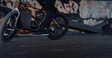 Sporty man riding bmx bike at skatepark. Bmx rider performing trick outdoors.