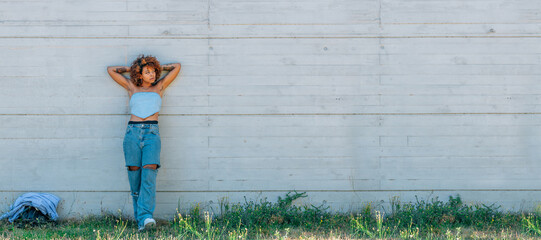 Wall Mural - relaxed latin girl leaning on street wall outdoors