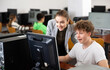 © JackF - Smiling friendly female teacher talking to cheerful teenager studying in college computer lab..