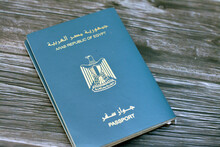 Egyptian Passport Isolated On Wooden Background, Arab Republic Of Egypt's Passport With The Republican Golden Eagle On Its Cover And King Tutankhamun Mask Mark On The Inside Identity Papers