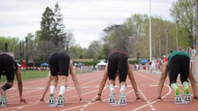 Static Shot Of Track And Field Sprint Race With A Black Man And White Man Racing. They Stay In The Starting Blocks And Begin To Sprint Once The Starter Fires The Gun