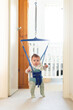 © Austockphoto - Baby playing in jolly jumper bouncing toy in doorway