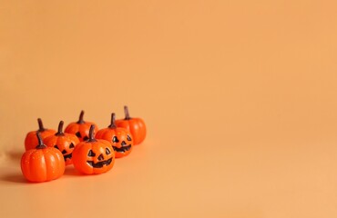 Wall Mural - small Beautiful pumpkins on a orange background. Creative halloween concept backdrop. halloween pumpkin toy.	