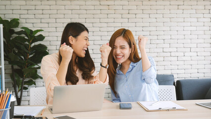 Wall Mural - Two businesswomen team meeting using laptop at company office desk. Two young Female freelance reading financial graph charts Planning analyzing marketing data. Asian people team working office firm.