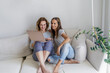 © Westend61 - Smiling lesbian couple sharing laptop sitting on sofa at home