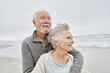 © Westend61 - Happy senior couple standing smiling on windy beach