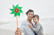 © Westend61 - Father carrying son on the beach holding green pinwheel