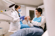 © ADDICTIVE STOCK - Dentist talking to patient on medical chair in clinic