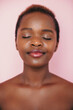 © Strelciuc - Front view of an African American woman smiling with closed eyes posing on pink background representing spa service. Attractive beautiful girl. Young woman face
