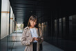 © ADDICTIVE STOCK - Young woman in earphones browsing phone near building