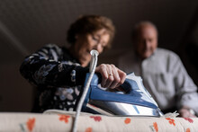 Elderly Couple Ironing Clothes In Room