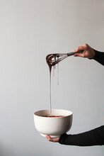 Crop Hands Draining Chocolate From A Whisk