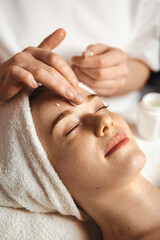 Wall Mural - beautician applying cosmetic cream on patient's face at spa salon. happy face. skin treatment. facia