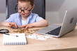 © Александра Алероева - A little boy in a blue shirt and glasses counts money, euros, cents.