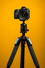 Dslr Camera On Tripod Isolated With Yellow Background