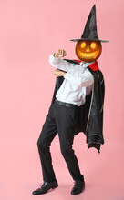 Man With Carved Pumpkin Instead Of His Head On Pink Background. Halloween Celebration
