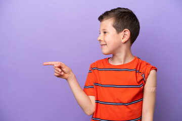 Wall Mural - Little boy wearing a band aid isolated on purple background pointing to the side to present a product