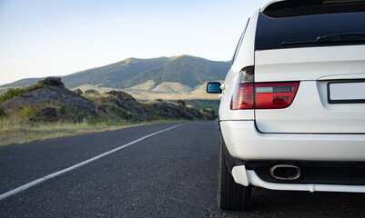 Wall Mural - White car moves on the road among the mountains