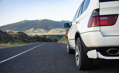 Wall Mural - White car moves on the road among the mountains