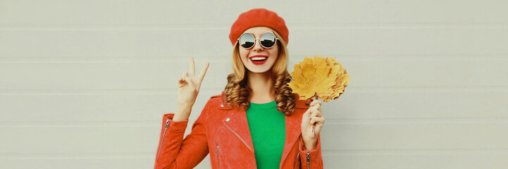 autumn portrait of happy smiling young woman with yellow maple leaves wearing red french beret on gr