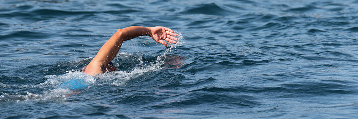 Wall Mural - Woman swimmer swimming crawl in blue sea, triathlon competition