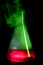 Strong Chemical Reaction With A Lot Smoke And Vapors Inside Erlenmeyer Flask. School Chemical Experiment Vessel With A Red Liquid And Green Smoke. Background Picture.