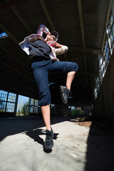 Wall Mural - Young female hip hop dancer dancing and jumping in abandoned building on a sunny summer day	
