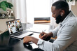 © Kateryna - Group video meeting. Successful african american man, sit at a desk in the office or at home, talking on a video conference with colleagues, discuss new ideas and financial plan, strategy, takes notes