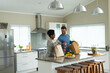 © Wavebreak Media - Image of happy diverse couple unpacking groceries in kitchen
