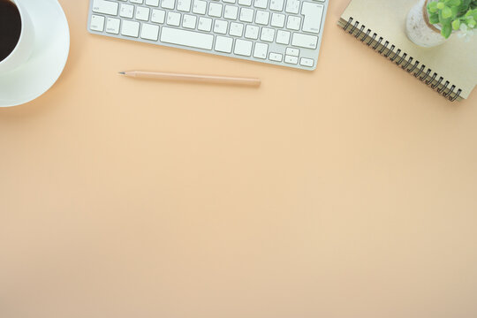 Flat lay of top view desk work table with Coffee computer notebook and pencil work space in minimal orange color autumn tone concept includes copyspace for add text or graphic