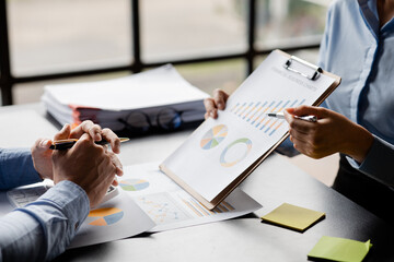 Company meeting room has businessmen and finance managers meeting together on finance topics, they are looking at information on documents and discussing together. Concept company financial management