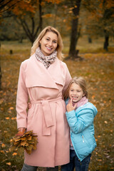 Mother with daughter walking and having fun in autumn park