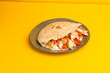 Shawarma in a pit with vegetables and chicken, side view yellow background