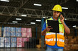 factory worker holding a clipboard and talking on smartphone to customer in the warehouse factory