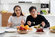 © atitaph - young Asian couple Happy to sit and eat at the dining table in the kitchen at home