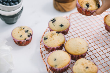 Poster - Homemade blueberry muffins baked to perfection on cooling rack in modern white marble kitchen.