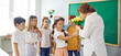 © Studio Romantic - Cute schoolchildren with flowers for their best female teacher at school in honor of holiday. Preteen classmates in classroom give teacher bouquet of tulips. Teacher's day concept. Web banner.