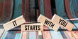 IT STARTS WITH YOU text written on wooden blocks and vintage background