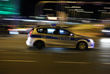 Fototapeta Miasto - Radiowóz polskiej policji na sygnałach alarmowo szybko jedzie przez miasto na interwencję. 