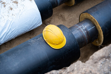 Large water and sewer a new tube pipe at construction site, stacked pvc plastic pipe. Engineering communication system construction. A yellow construction helmet lies on the pipe.