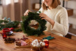 © Syda Productions - winter holidays, diy and hobby concept - close up of happy smiling woman with fir branches making christmas wreath at home
