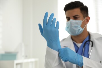 Canvas Print - Doctor in protective mask putting on medical gloves in office