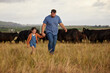 Farmer father, child or family with cows on a farm, grass field or countryside. Sustainability or environmental dad and girl with cattle in background for meat, beef or agriculture growth industry