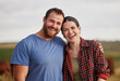 © Nina Lawrenson/peopleimages.com - Happy, carefree, and excited farmer couple standing outdoors on cattle or livestock farmland. Portrait of relaxed lovers relaxing on organic or sustainable land smiling and enjoying nature