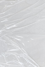 White Transparent Crumpled And Creased Plastic Poster Texture Background. Wet Plastic Wrap On The White Background
